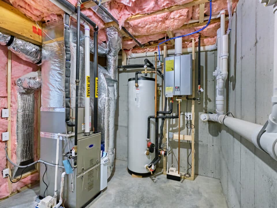 Unfinished basement mechanical room with tankless water heater, storage tank, plumbing and heating systems